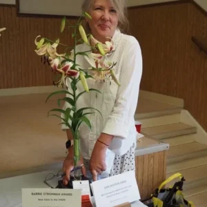 A woman standing next to a plant with flowers.