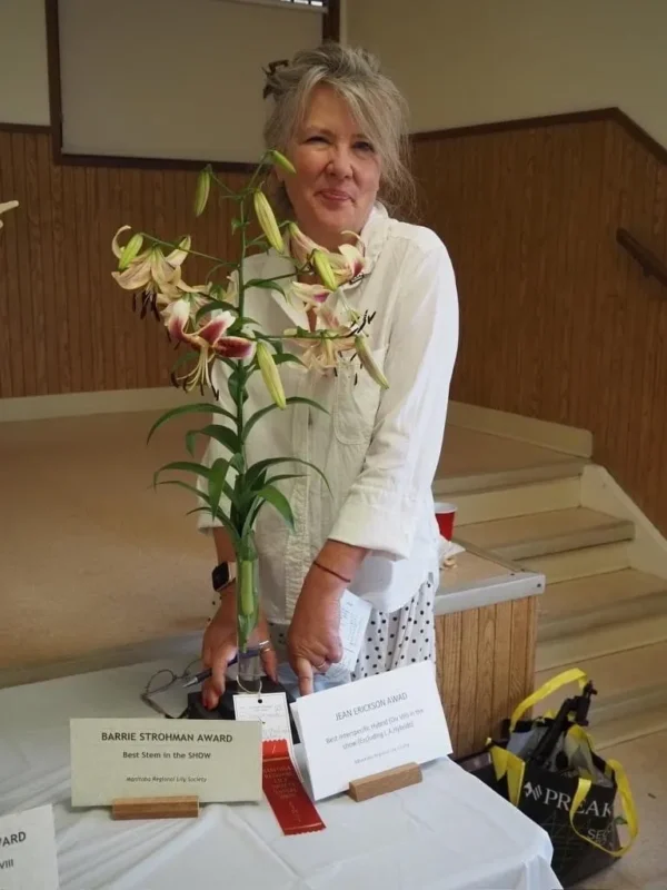 A woman standing next to a plant with flowers.