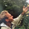 Man admiring yellow lilies outdoors.