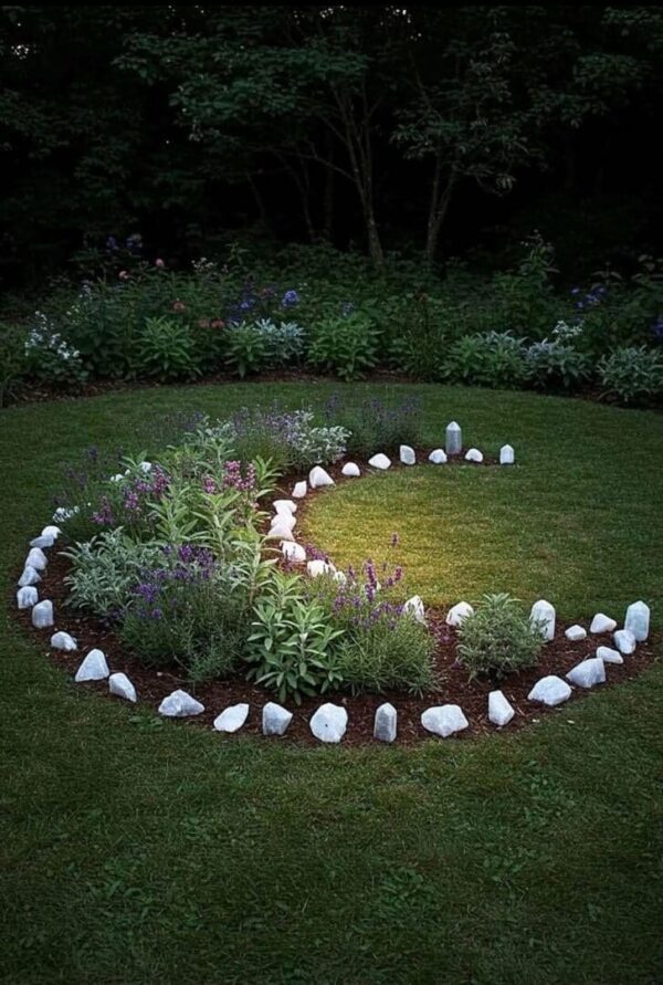Spiral garden design with white stones and plants on green grass.