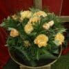Yellow carnations arranged in a green leafy basket.