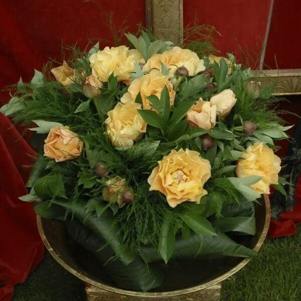 Yellow carnations arranged in a green leafy basket.