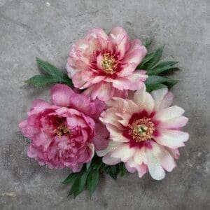 Three pink flowers with green leaves on a gray surface.