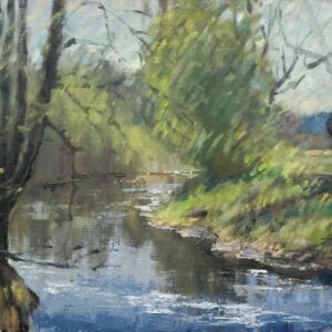 A serene riverside scene with trees and calm water reflecting the sky.