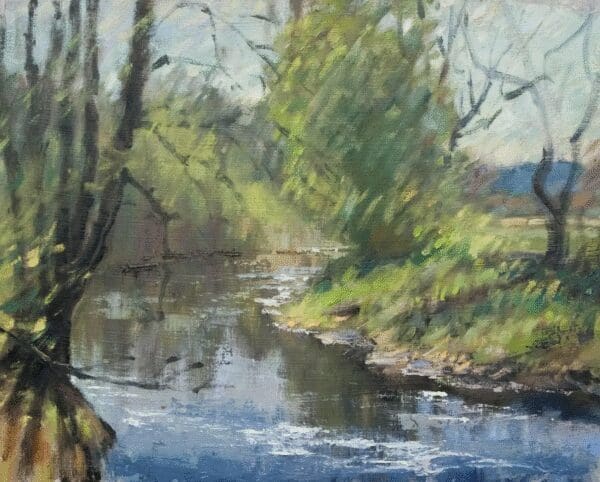 A serene riverside scene with trees and calm water reflecting the sky.