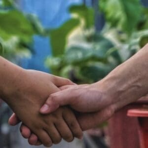 Two people holding hands in a gentle gesture.