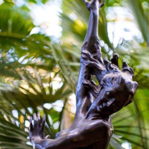 Bronze dancing woman statue among palm leaves